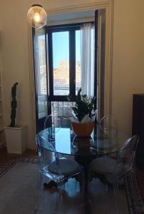 comedor con mesa de cristal, sillas y ventana en Living Suite Catania Ursino, en Catania