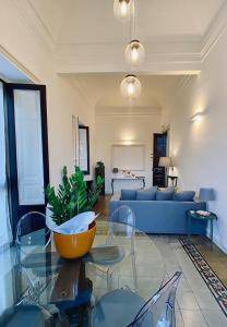 Una sala de estar con un sofá azul y una mesa de cristal. en Living Suite Catania Ursino, en Catania