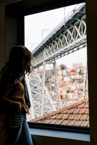 Una donna che guarda fuori dalla finestra di un ponte di Oh! Porto Apartments a Vila Nova de Gaia