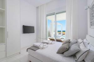 a white bedroom with a large bed and a window at Seashore Beachfront Villa in Lachania