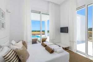 a white living room with a white couch and a television at Seashore Beachfront Villa in Lachania