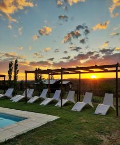 una fila de sillones blancos junto a una piscina en Piedramora en Villa Giardino