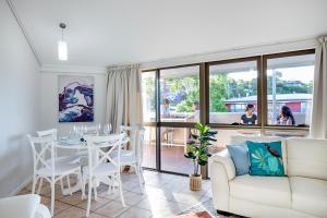 a living room with a couch and a table and chairs at Heart of Airlie Beach Apartment in Airlie Beach