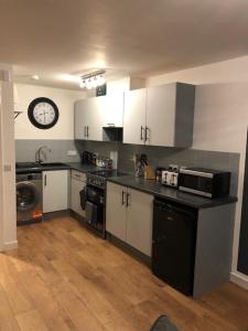 a kitchen with white cabinets and a clock on the wall at GRAPHITE APARTMENTS in Inverness