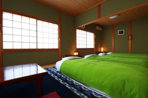吉野的住宿－美吉野櫻庵賓館，带三张床、绿色床单和窗户的客房