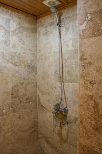 a shower in a bathroom with a stone wall at Melek Cave Hotel in Goreme