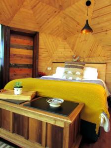 a bedroom with a bed with a yellow blanket on it at Glamping Cantabria in Tunja