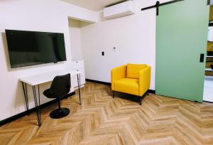 a living room with a tv and a yellow chair at The Bell Vista in Burbank