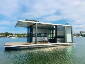 a small house on a dock in the water at oasis noosa - luxury floating eco villas in Noosa Heads