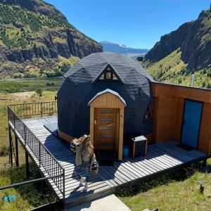 a dog sitting on the steps of a black dome house at Domo Carpe diem Patagonia in Coihaique