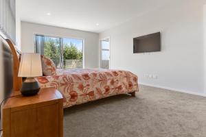 a living room with a couch and a television at Picturesque Papamoa - Papamoa Holiday Home in Papamoa