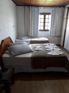Dos camas en un dormitorio con toallas. en Pousada Cravo e Canela SJ, en São Joaquim