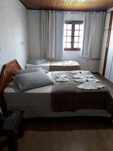 two beds in a bedroom with towels on them at Pousada Cravo e Canela SJ in São Joaquim