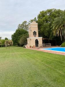 een gebouw in het midden van een tuin met een zwembad bij Don Aniceto - Suites de Campo in Luján