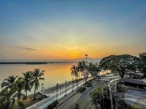 zachód słońca nad rzeką z palmami i ulicą w obiekcie Baan Arunothai Homestay w mieście Phayao
