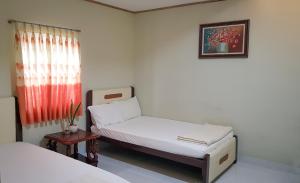 niewielka sypialnia z 2 łóżkami i oknem w obiekcie Khang Bảo Viên w mieście Củ Chi