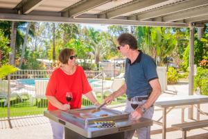 a man and a woman standing in front of a grill at BIG4 Whitsundays Tropical Eco Resort in Airlie Beach