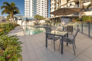 a patio with a table and chairs next to a pool at The Waterford Prestige Apartments in Caloundra