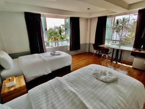 a hotel room with two beds and a desk and windows at Baan Arunothai Homestay in Phayao