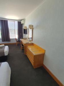 a room with a bed, chair, desk and a mirror at Capital Airport Motel in Queanbeyan