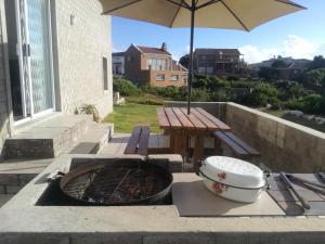a patio with a grill and a picnic table with an umbrella at Gansbaai Self-Catering Apartment in Gansbaai