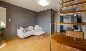 a living room with a couch and a loft bed at Pampas Hotel Jeju in Jeju