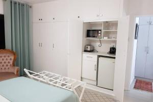 a white room with a bed and a kitchen at 16 Flame@ Supertubes, Luxury room, Jeffreys Bay in Jeffreys Bay