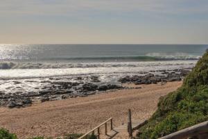 a beach with a staircase leading to the ocean at 16 Flame@ Supertubes, Luxury room, Jeffreys Bay in Jeffreys Bay