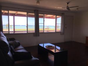 a living room with a couch and a table and windows at Best Beach Villa in Denham