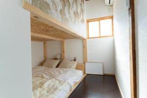 um pequeno quarto com uma cama e uma janela em Guesthouse & Kitchen Hace em Iwaki