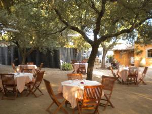 ein Restaurant mit Tischen und Stühlen unter einem Baum in der Unterkunft Su Barroccu in Riola Sardo