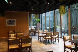 a dining room with tables and chairs and windows at Amara Bangkok Hotel in Bangkok