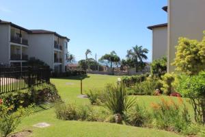 a garden in front of a building with palm trees at 7 Topanga in Uvongo Beach