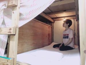 a young boy sitting on a bed in a bunk bed at Guest House Cam Cam Okinawa in Naha