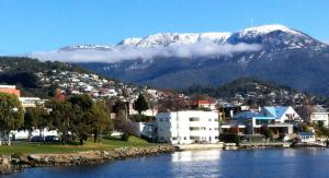 a town with a snow covered mountain in the background at Cosy Apartment accommodation in Hobart, New Town. in New Town