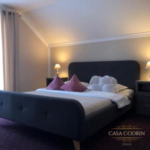 1 dormitorio con 1 cama grande con almohadas moradas y blancas en Casa Codrin, en Bran