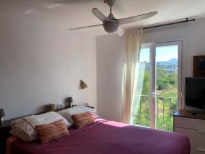 a bedroom with a bed with a ceiling fan and a window at Ático a 200m del mar. in Jávea +29 photos