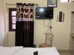 um quarto com uma cama, uma televisão e uma janela em Baddi Guest House em Baddi