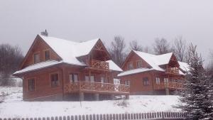 ein großes Haus mit Schnee auf dem Dach in der Unterkunft Słoneczne Chaty Kasina Wielka in Kasina Wielka