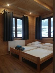 two beds in a room with two windows at Słoneczne Chaty Kasina Wielka in Kasina Wielka