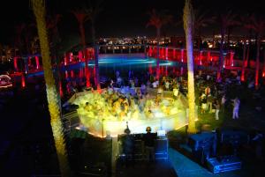 Un groupe de personnes debout autour d'une piscine la nuit dans l'établissement Sharm Dreams Vacation Club - Aqua Park, à Charm el-Cheikh