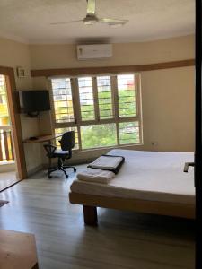 een slaapkamer met een bed en een bureau met een stoel bij Ballygunge Guest House in Calcutta