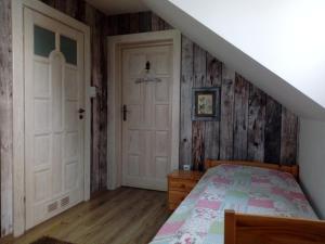sypialnia z łóżkiem i drewnianą ścianą w obiekcie Roztoczański Dworek w mieście Zamość