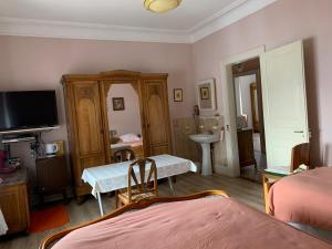 a bedroom with a bed and a table and a tv at Chambre Gentiane 2 à 3 personnes wifi sdb partagée in Saint-Amarin