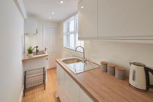 a white kitchen with a sink and a counter at Host & Stay - Fountains Cottage in Guisborough