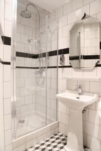 La salle de bains blanche est pourvue d'un lavabo et d'une douche. dans l'établissement Hotel André Latin, à Paris