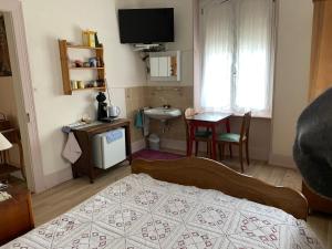 um quarto com uma cama, uma mesa e um lavatório em Chambre Arnica lit 140 wifi sdb partagée em Saint-Amarin