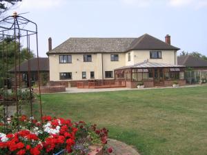 una casa grande con cenador y algunas flores en Pointers Guest House, en Wistow