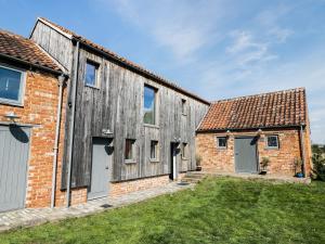 dos viejos graneros con puertas blancas y césped verde en Finest Retreats - Oak House, en Tealby