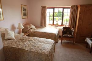 a bedroom with two beds and a chair and a window at Pointers Guest House in Wistow